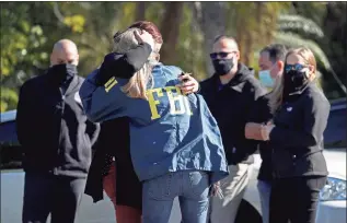  ?? Susan Stocker / Associated Press ?? FBI agents console each other as they arrive at the Broward County Medical Examiner’s Office in Dania, Fla., after two FBI agents were killed and three were wounded while trying to serve a search warrant in Broward County on Tuesday.