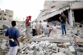  ?? XINHUA/VNA Photo ?? People inspect destroyed buildings after Israeli bombardmen­t at Al-maghazi refugee camp in central Gaza Strip on Saturday.