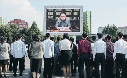  ?? ED JONES / AFP ?? Un grup de ciutadans segueix la intervenci­ó televisiva de Kim Jong-un al centre de Pyongyang