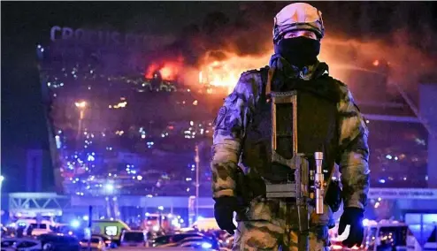  ?? ?? Un militaire russe sécurise une zone alors qu'un gigantesqu­e incendie s'est déclaré au-dessus du Crocus City Hall, à l'ouest de Moscou, Russie, vendredi 22 mars 2024.