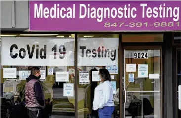  ?? ?? An Exam Corp Lab employee wears a mask as she talks with a patient lined up for COVID-19 testing in Niles, Illinois. If a mandate is upheld, companies with at least 100 workers will be required to give employees paid time off to get vaccinated against COVID-19 and paid sick leave if they have side effects from the shots.