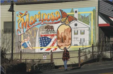  ??  ?? A person walks in front of a Mariposa mural along Main Street in downtown Mariposa.