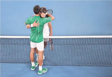  ?? GETTY IMAGES ?? Serbia's Novak Djokovic (in green) embraces Austria's Dominic Thiem after winning the Australian Open men's singles title Sunday. It was Djokovic's eighth Australian Open title and second in a row.