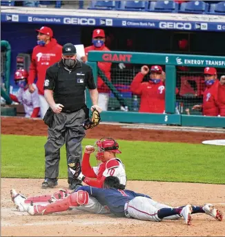  ?? MATT SLOCUM/AP ?? Phillies catcher J.T. Realmuto celebrates after tagging out Braves second baseman Ozzie Albies, who was trying to score on a flyout in the 10th inning Thursday. The Phillies won 3-2 in 10 innings.