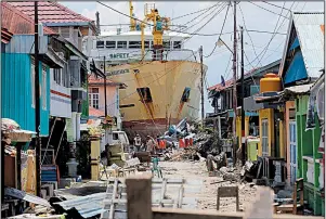  ?? AP/TATAN SYUFLANA ?? A ship swept ashore by Friday’s tsunami sits in the middle of a neighborho­od Tuesday in Donggala in Central Sulawesi, Indonesia. People in the Donggala region say they are not getting help after the disaster.