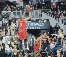  ?? NICK WASS THE ASSOCIATED PRESS ?? Raptors’ Serge Ibaka shoots late in double overtime over Wizards’Otto Porter Jr. and Tomas Satoransky on Sunday. Toronto won, 140-138.