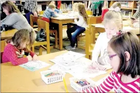  ?? Photos by Lynn Atkins/The Weekly Vista ?? (Above) A Christmas movie was playing in the school library where coloring sheets and crayons were laid out during Brunch with Santa at Cooper Elementary on Saturday. (Right) Elijah and Shanel Huston posed with Santa while their mom, Sharee Huston,...