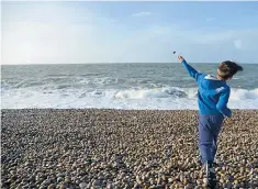  ??  ?? Stone Age instinct? A boy throws a pebble into the sea on Chesil Beach in Dorset