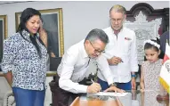  ?? JOHN ROBLEDO ?? Carlos Prasca firma el acta de posesión. Lo observan el gobernador Verano, Katia Ruiz y la niña Valentina Segura.