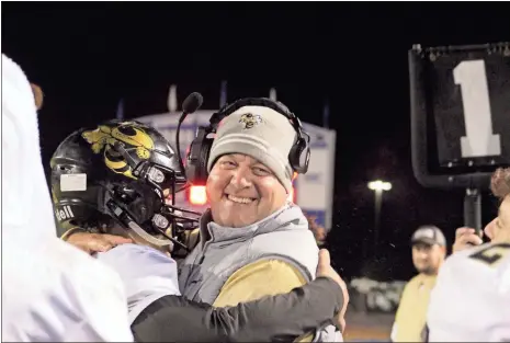  ?? / Kevin Myrick ?? Quarterbac­k Dylan Bailey gives Head Coach Biff Parson a hug after a cooler bath on the sidelines as their 61-6 win over Model came to a close.