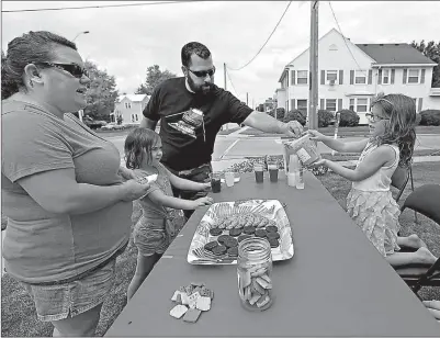  ?? Doug Raflik/The Reporter via AP ?? Heather, Abigayle and Paul Quickle donate money to Jaelle Weinberger’s cause to help feed hungry people in Africa Aug. 9 in Waupun, Wis. Jaelle set up a lemonade/cookie stand for two hours and raised more than $60 to help provide 254 meals through the Childrens Hunger Fund.