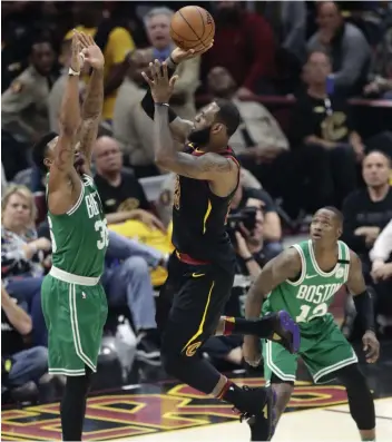  ?? AP ?? LeBron James ( centre) of Cleveland Cavaliers goes up to shoot against Marcus Smart ( left) and Terry Rozier of Boston Celtics in their NBA Eastern Conference finals in Cleveland on Monday. The Cavaliers won 111- 102. —