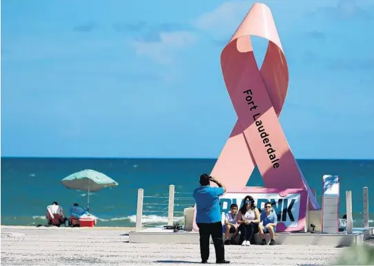  ?? AMY BETH BENNETT/SUN SENTINEL ?? The Juarez family, from left; Mario, Mario, Jr., 8, Betcy, and Matthew, 9, visiting on a day trip from Cape Coral, take a photograph with the Auto Nation Drive Pink statue on Fort Lauderdale Beach on Monday. A sign says Auto Nation will make a donation to breast cancer research for each photograph beachgoers share on social media with #DrivePink. October is National Breast Cancer Awareness Month.