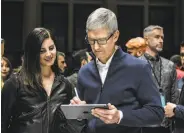  ?? Stephanie Keith / Getty Images ?? Singer Lana Del Rey watches Apple CEO Tim Cook work on a new iPad at the New York event.