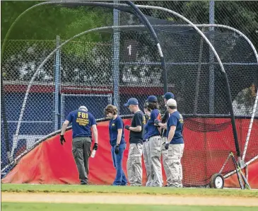  ?? AL DRAGO / NEW YORK TIMES ?? FBI personnel search near a batting cage at the Eugene Simpson Stadium Park after the mass shooting Wednesday in Alexandria, Va. President Donald Trump and congressio­nal leaders issued calls for unity.