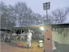  ??  ?? Villager Mohan Bharwad poses next to a compact fluorescen­t lamp (CFL)
powered by solar energy, outside his house on the outskirts of Gandhinaga­r, India.