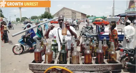  ?? — AFP ?? A street vendor holds a bottle of petrol while people move on a street of Bouake, Ivory Coast.