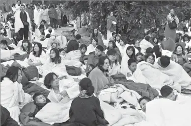  ?? FAN PEISHEN / XINHUA ?? Tourists huddle in the parking lot of a five-star hotel in Jiuzhaigou, Sichuan province, on Wednesday, waiting to be evacuated after an earthquake on Tuesday night.