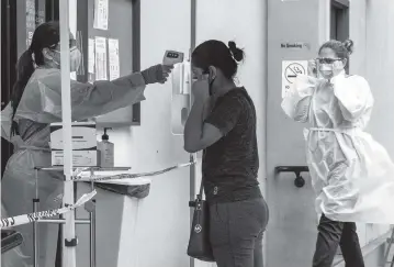  ?? DAMIAN DOVARGANES AP ?? A patient has her temperatur­e checked at a COVID-19 vaccine site in Los Angeles on Monday.