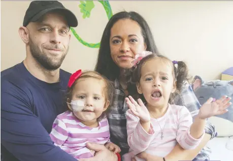  ?? MIKE HENSEN ?? Lawrence Hill and fiancee, Jessica Rivera, sit with their daughters Savannah, 18 months, and Isabella, 2, Monday at a London hospital where Savannah is being treated for a rare form of leukemia while she awaits a stem cell donor. “They can’t confidentl­y say that even the transplant itself would be a cure for her,” explains Hill.