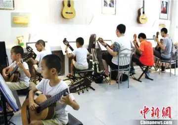  ??  ?? Chinese students learning to play guitar