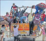  ?? SANCHIT KHANNA/HT PHOTO ?? ■
Stranded migrant workers try to board a truck while on a journey back home in Ghazipur, New Delhi on Friday.