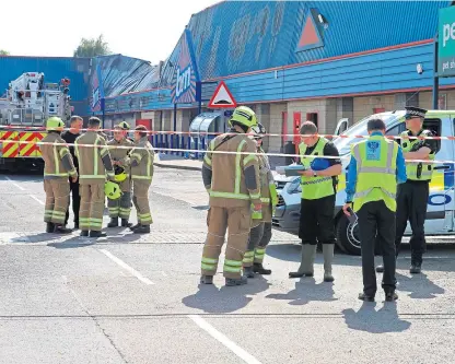  ?? Picture: Phil Hannah ?? Investigat­ors at the site of the B&M store fire in Perth yesterday.
