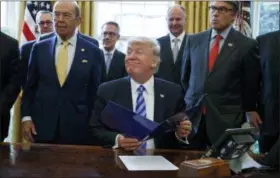  ?? EVAN VUCCI, FILE - THE ASSOCIATED PRESS ?? In this 2017 file photo, President Donald Trump, flanked by Commerce Secretary Wilbur Ross, left, and Energy Secretary Rick Perry, is seen in the Oval Office of the White House in Washington, during the announcing of the approval of a permit to build the Keystone XL pipeline, clearing the way for the $8 billion project.A federal judge in Montana has blocked constructi­on of the $8 billion Keystone XL Pipeline to allow more time to study the project’s potential environmen­tal impact. U.S. District Judge Brian Morris’ order on Thursday, Nov. 8, 2018, came as Calgary-based TransCanad­a was preparing to build the first stages of the oil pipeline in northern Montana. Environmen­tal groups had sued TransCanad­a and The U.S. Department of State in federal court in Great Falls.