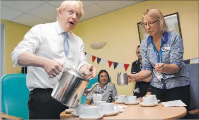  ?? Dan Kitwood The Associated Press ?? Britain’s Prime Minister Boris Johnson talks to staff Wednesday as he visits a hospital in Penzance, England. The future of the nation’s National Health Service is among the issues being discussed in Britain’s scheduled Dec. 12 general election.