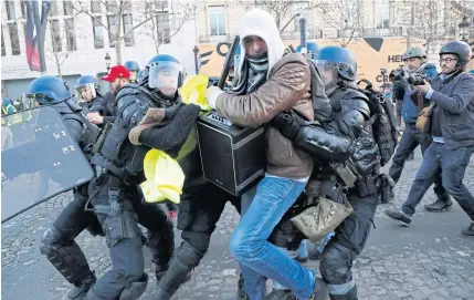  ??  ?? GROWING REVOLT: Police apprehend a “yellow vest” demonstrat­or on the Champs Elysees in Paris yesterday.