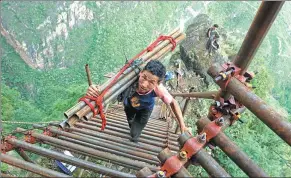  ?? PROVIDED TO CHINA DAILY ?? Above: Mose Xiongti, 21, of Atuleer village, carries materials used in constructi­ng a steel ladder that villagers soon will use to more safely traverse an 800-meter cliff to their homes. The village is in Liangshan Yi autonomous prefecture, Sichuan...