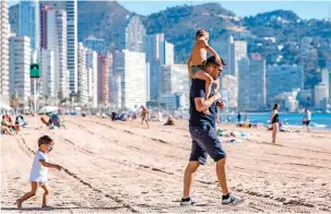  ?? ?? Balmy: A family hits the beach in Benidorm this week to soak up some rays