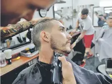  ??  ?? A barber cuts a client beard in a barbershop of Havana.