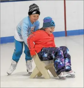  ??  ?? Child pushes a friend across the ice on a chair at the Thomas Eccleston Jr. Rink during free community skating at The Hill School in Pottstown.