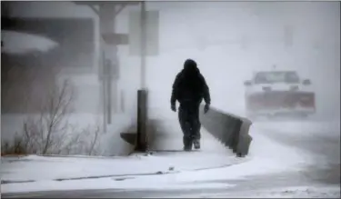  ?? JACOB BYK — THE WYOMING TRIBUNE EAGLE VIA AP ?? A man crosses Crow Creek during a blizzard on Wednesday in Cheyenne, Wyo. Heavy snow hit Cheyenne about midmorning Wednesday and was spreading into Colorado and Nebraska.