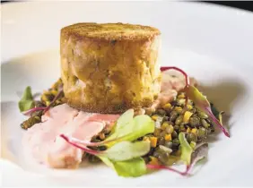  ??  ?? Above: Duck confit is pressed into a crisp patty on top of a pink slice of pork belly, a bed of lentils and a few minuscule greens.