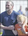  ??  ?? Joey Taylor walks with his daughter, Josie Taylor, who was evacuated to a church following a shooting at Townville Elementary School.