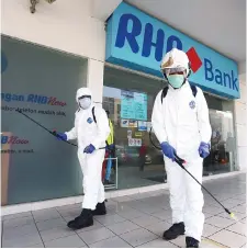  ?? — Photo by Muhd Rais Sanusi ?? Bomba personnel carrying out the sanitisati­on exercise at the bank branch in Satok.