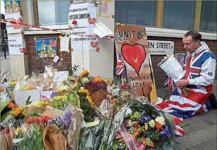  ??  ?? Drapé de l’Union Jack, un homme dépose des fleurs près du lieu de l’attentat commis, samedi, à Londres.