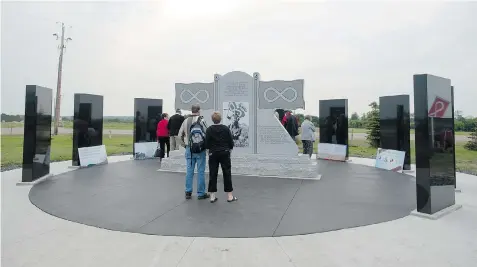  ?? PHOTOS: LIAM RICHARDS/THE StarPhoeni­x ?? Visitors look at a new monument that recognizes Metis veterans from the 1885 resistance up to the Korean War Saturday during Back to Batoche Days.