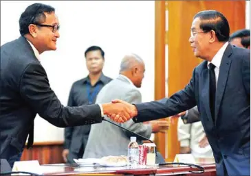  ?? AFP ?? Prime Minister Hun Sen (right) shakes hands with former leader of CNRP Sam Rainsy during a meeting at the National Assembly in Phnom Penh in 2013.