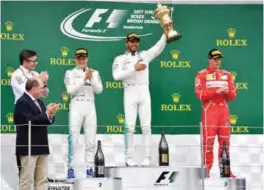  ??  ?? SILVERSTON­E: Winner Mercedes’ British driver Lewis Hamilton (2R) celebrates with his trophy on the podium next to second placed Mercedes’ Finnish driver Valtteri Bottas (C) and third placed Ferrari’s Finnish driver Kimi Raikkonen (R) after the British...