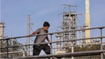  ?? Jon Shapley/Staff file photo ?? A child climbs on bleachers at Hartman Park with the Valero Houston Refinery in the background. Many Texas families are dealing with a legacy of environmen­tal injustice.