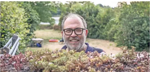  ?? RP-FOTO: HANS-JÜRGEN BAUER ?? Er behält den Überblick: Marcus Hecker schaut von der Leiter über sein bepflanzte­s Dach. Dort will er zwei Bienenkörb­e aufstellen.