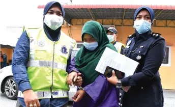  ?? — Bernama photo ?? Two policewome­n escort the student.