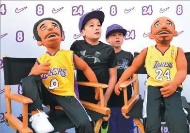  ?? HARRY HOW / AGENCE FRANCE-PRESSE BASEBALL ?? Young fans pose for a photo at the “Kobeland” street fair ahead of a jersey retirement ceremony to honor Los Angeles Lakers legend Kobe Bryant at Staples Center in Los Angeles on Monday.