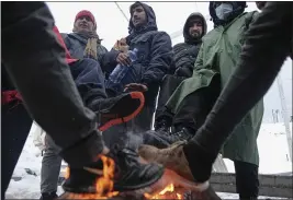  ?? PHOTOS BY KEMAL SOFTIC — THE ASSOCIATED PRESS ?? Migrants warm their feet by a fire at the Lipa camp northweste­rn Bosnia, near the border with Croatia, Saturday.