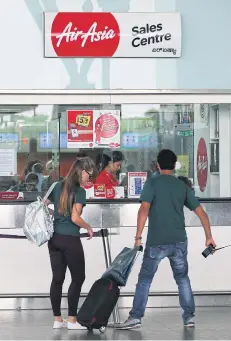  ?? AP ?? A passenger removes the barrier tape to reach the sales centre of AirAsia at Kempegowda Internatio­nal Airport in Bangalore, India yesterday.