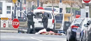  ??  ?? Uniformed US Secret Service officers, including a photograph­er, investigat­e after a passenger vehicle struck a security barrier near the White House in Washington. — Reuters photo