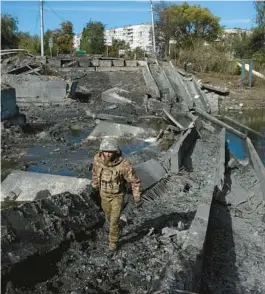  ?? TYLER HICKS/THE NEW YORK TIMES 2022 ?? A Ukrainian soldier walks across the wreckage of an important bridge Sept. 24 in Bakhmut. The battle for the city was underway in earnest by August.